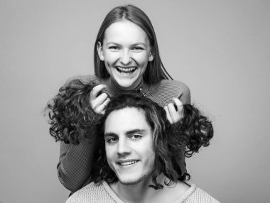 Birlikte eğlenceli vakit geçiriyoruz. Çiftler halinde neşeli anlar. Erkek arkadaşının kıvırcık saçlarını tutan neşeli kız onu komik saç stillerine dönüştürüyor..