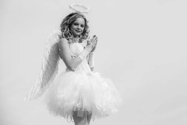 Belleza azul sus ojos encantadora dama en el cielo la luz del sol. Niña con alas de ángel y halo. Inocente chica con alas de ángel de pie con arco y flecha contra el cielo azul y nubes blancas. — Foto de Stock