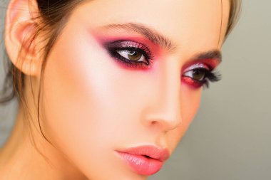 Stüdyoda gri arka planda güzel bir kadın var. Yakın plan portre. Moda, güzellik, kozmetik. Makyaj, pürüzsüz cilt.