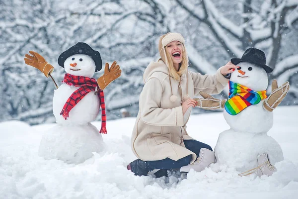 Legrační sněhuláci. Šťastná usměvavá dívka, aby sněhulák na slunné zimní den. Lidé ve sněhu. Sněhulák. Krása Zimní dívka se sněhulákem v mrazivém zimním parku. — Stock fotografie