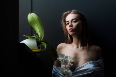 Orkide çiçekli şehvetli kız. Seksi kadın ve siyah üzerine orkideler..