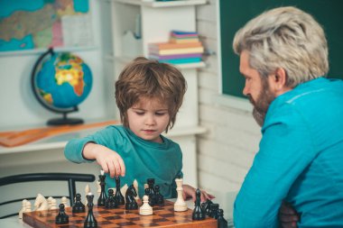 Satranç stratejisi geliştiren konsantre bir çocuk. Satranç stratejisi geliştiren sevimli çocuk. Yakışıklı öğretmen anaokulu çocuğuna özel ders veriyor..