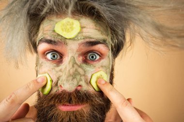 Kil maskenin üzerine salatalık dilimleri uygulayan adamın komik yüzü, sabah spa prosedürü, kapanış..