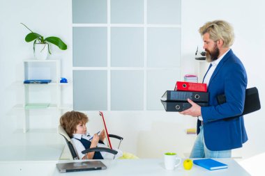 Patron ve iş adamı ofiste birlikte çalışıyorlar. Ofisteki bir iş masasında patronluk taslayan küçük çocuk..