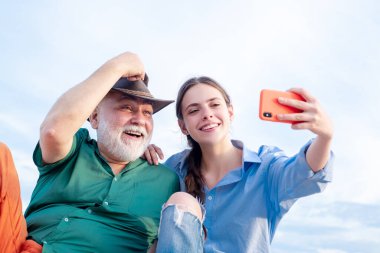 Yaşlı adam ve güzel genç kız sarılıp selfie çekiyorlar. Yaşlı, nazik büyükbabasından torunu var. Fotoğraf çeken ya da video çeken akrabalar. Olgun babalı kız..