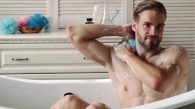 Banyoda bornozla yıkanan seksi genç adam. Hijyen ve kaplıca. Seksi sporcu kaslı adam. Çıplak gövde..