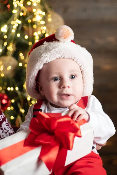 Porträt eines lustigen Babys in Nikolauskleidung und Weihnachtsmütze. Spaß im neuen Jahr. — Stockfoto