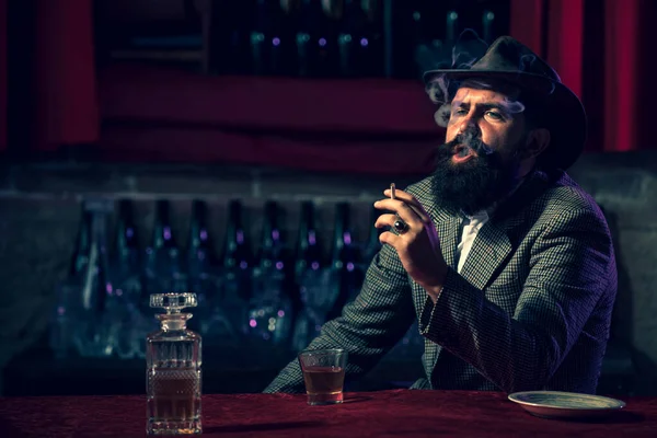 Привлекательный мужчина курит сигареты со стаканом виски. — стоковое фото