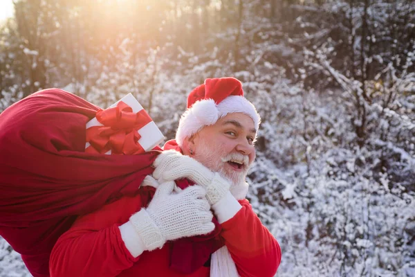 Père Noël marchant vers la forêt d'hiver avec un sac de cadeaux, paysage de neige. Bonne année. — Photo