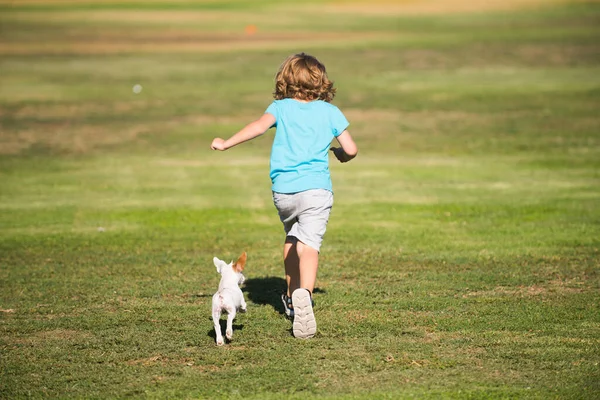 Ευτυχισμένο παιδί τρέχει με ένα σκυλί υπαίθριο. — Φωτογραφία Αρχείου