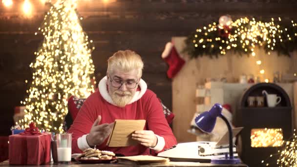 Der Weihnachtsmann im hölzernen Hausinneren liest Wunschzettel. Lieber Weihnachtsmann. — Stockvideo