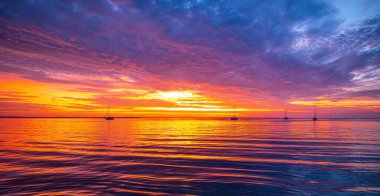 Okyanusta gün batımı ya da gün doğumu, doğa manzarası. Pembe bulutlar gökyüzünde parlayan güneşe doğru uçuyor. Akşam ya da sabah manzarası.