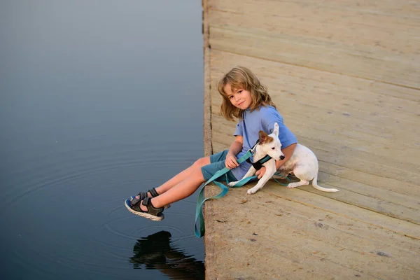Het kind droomt. Gelukkig kind in het park met hond bij het meer. — Stockfoto