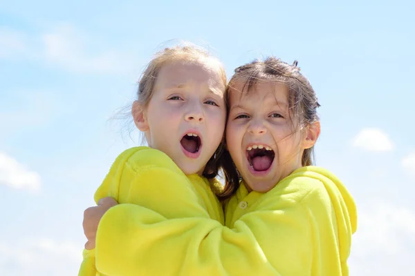 Lustige Kindergesichter von zwei niedlichen kleinen Kindern, die sich umarmen. Lustige schöne Kinder umarmen sich. Mädchenhafte Freizeit. — Stockfoto