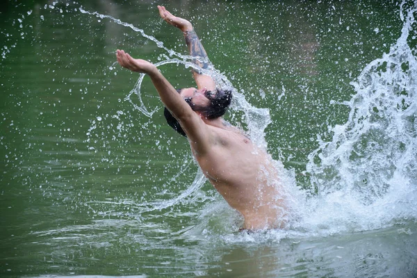 L'homme barbu saute hors de l'eau, éclaboussant pendant les vacances d'été. Guy éclaboussant l'eau par ses cheveux mouillés et sa barbe sur le visage en s'amusant. — Photo