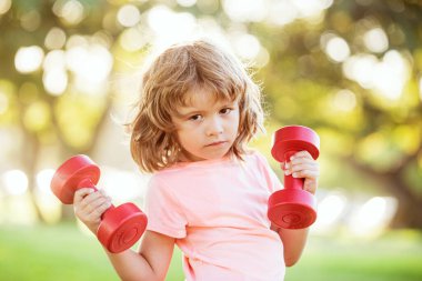 Çocuklar dışarıda halterlerle egzersiz yapıyor. Çocuk için spor.