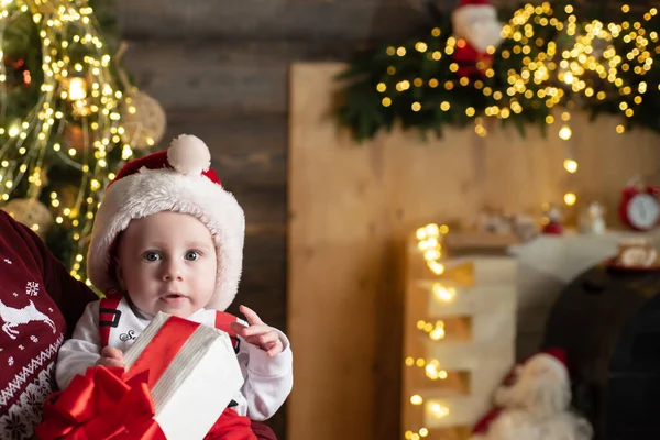 Weihnachtsporträt des süßen kleinen Babys mit Weihnachtsmütze hält Geschenk. — Stockfoto