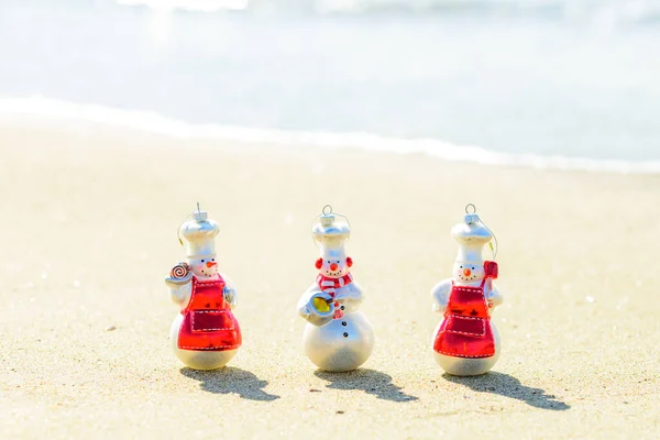 Szczęśliwego Nowego Roku i świątecznej podróży. Snow man na plaży morskiej. — Zdjęcie stockowe