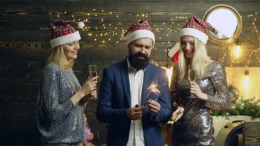 Parlak bengal ışıklarıyla şampanya içen bir grup insan. Komik grup yeni yılı kutluyor. Noel partisi.