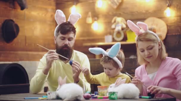 Szczęśliwego Wielkanocy. Rodzina malowała jajka. Ojciec, matka i syn noszą królicze uszy. — Wideo stockowe