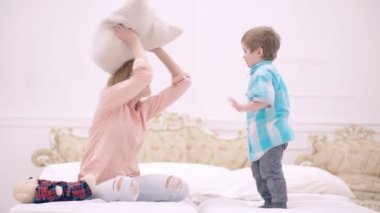 Anne ve oğlu yatakta oynuyor. Çocuk günü. Çocuk yardımı ve bakımı. Anne ve oğulun ilişkisi. Annen seni seviyor..