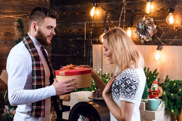 恋人には驚きだ。メリークリスマスと幸せな新年。クリスマスプレゼント。彼女のためのギフトボックス驚きと男ハンサムな。男ヒップスターは女の子クリスマスの装飾の背景に贈り物を与える — ストック写真