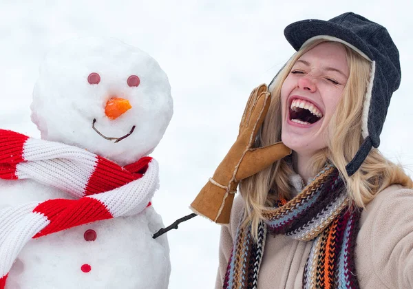 Winter love concept. Happy girl plaing with a snowman on a snowy winter walk. Making snowman and winter fun. Crazy comical face. — Stock Photo, Image