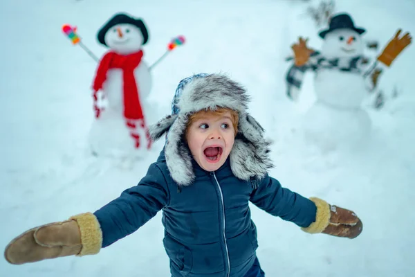 Portrait d'hiver du petit garçon enfant dans le jardin des neiges faire bonhomme de neige. Enfant jouant avec bonhomme de neige sur fond de neige. Enfants d'hiver dans le parc d'hiver givré. — Photo