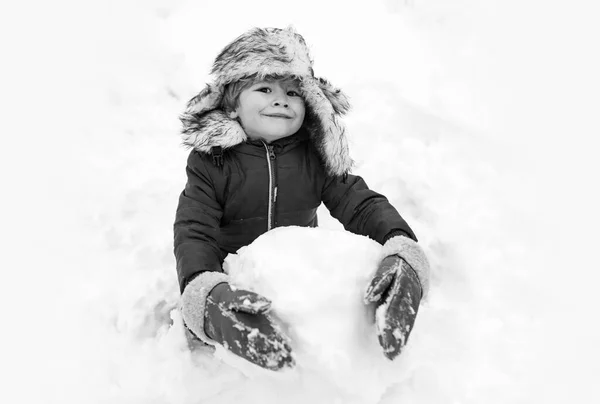 Schneemann und lustiges Kind, der Freund steht mit Wintermütze und Schal mit roter Nase da. Fröhliches Kind, das Spaß mit Schneemann im Winterpark hat. Winterbekleidung für Kinder. — Stockfoto