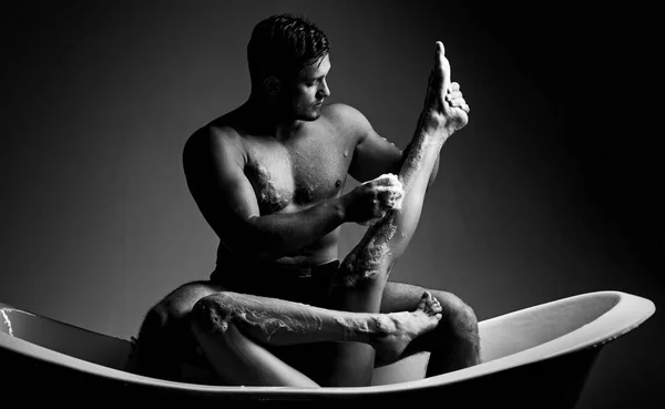 Couple aimant dans une salle de bain sur un fond noir. Femme sexy. Beau jeune homme sexy sensuel avec torse musculaire et beau corps assis sur la baignoire dans la salle de bain. Famille. — Photo