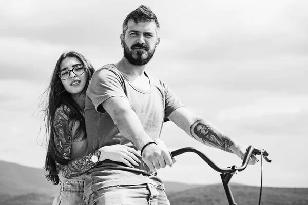 Belle fille souriante et homme hipster barbu est en vélo dans le parc. Couple à vélo sur une journée ensoleillée. Femme sexy avec vélo vintage dans une route de campagne. Relation. — Photo