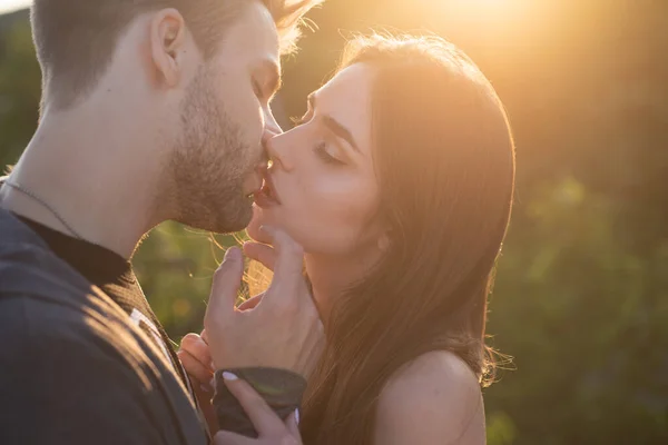 Mann mit Frau küsst. Nahaufnahme Porträt eines schönen jungen Paares, das darauf wartet, sich gegen das Licht des Sonnenuntergangs zu küssen. — Stockfoto