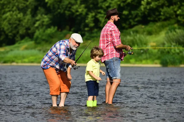 Fly fishing for trout. Great-grandfather and great-grandson. Grandfather, father and son are fly fishing on river. — Stock Photo, Image