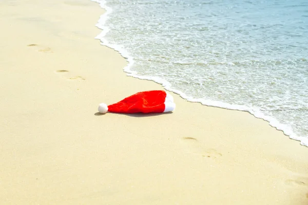 Chapéu de Pai Natal na areia. Natal e férias de Ano Novo em países quentes. Natal tropical. Férias de ano novo na praia tropical. — Fotografia de Stock