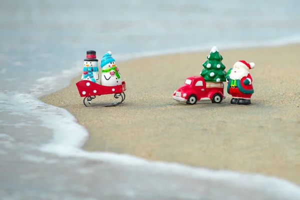 Zabawka Santa Claus na tle tropikalnego oceanu. Święta na gorących wakacjach. Ciepły klimat noworoczny, motyw plakatów, kartki okolicznościowe. — Zdjęcie stockowe