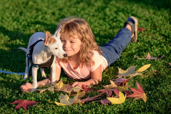 Grappig kind met hond in de herfst. Jongenswandeling met puppy op de herfst. — Stockfoto