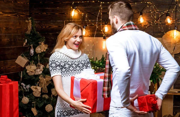Bright New Years interior. Christmas interior. Positive delighted loving couple giving each other Christmas gifts. Happy New Year. Christmas gifts. Celebrating New Year together. — Stock Photo, Image