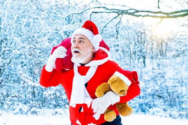 Äkta jultomten i röd mössa drar stora röda gåva säck. Julfirande semester. God Jul och Gott Nytt År konceptet. — Stockfoto