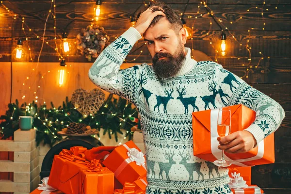 De kerstman wenst een vrolijk kerstfeest. Slechte kerstman met kerstmuts. Stijlvolle man met een lange baard poserend op de houten achtergrond. Gelukkig nieuwjaar. Kerstman cadeau geven. — Stockfoto