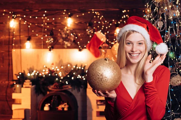 Het meisje versiert een kerstboom. Heel mooi blond meisje houdt bauble boven kerstboom. Vrolijk kerstfeest en gelukkig nieuwjaar. — Stockfoto