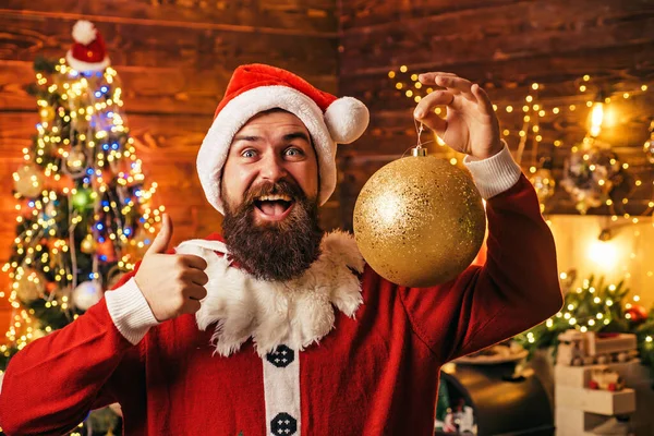 Gekke, grappige Hipster Kerstman. Portret van de gelukkige Kerstman met decoratieve speelgoed ballen in de buurt van de kerstboom. Gelukkig Kerstman gekleed in winterkleding denk aan Kerstmis of Nieuwjaar. — Stockfoto