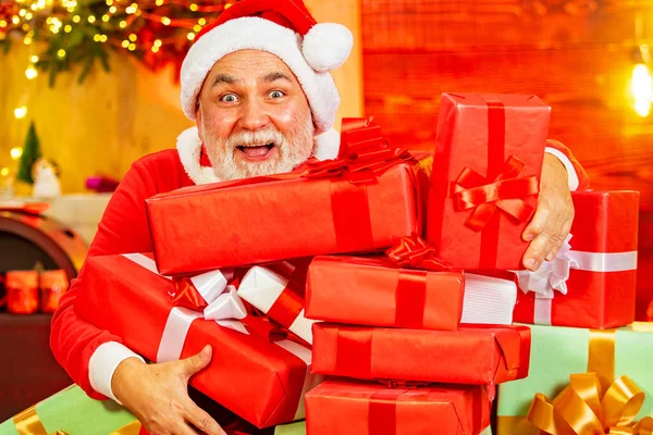 サンタとクリスマスプレゼント。サンタクロースとクリスマスグリーティングカード。サンタの祖父は白いひげがクリスマスの木製の背景にポーズをとっています。成熟したサンタクロースの肖像. — ストック写真