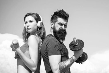 Dışarıda spor aletleriyle çalışan genç ve güçlü bir çift. Güzel mavi gökyüzü arka planında. Aktif yaşam tarzı ve spor aktiviteleri konsepti.