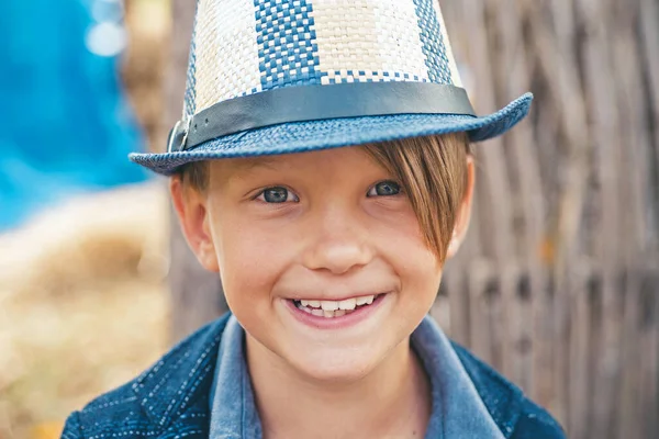 Lächelnder kleiner Junge, der mit Blättern spielt und in die Kamera schaut. Porträt aus nächster Nähe. Niedlicher kleiner Junge. — Stockfoto