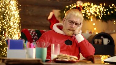 Noel Baba sıkıcı. Yorgun Noel Baba evde masada uyuyor..