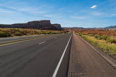 Classic American road running through the barren scenery of the Southwest with extreme heat haze on a hot sunny day with blue sky in summer. clipart