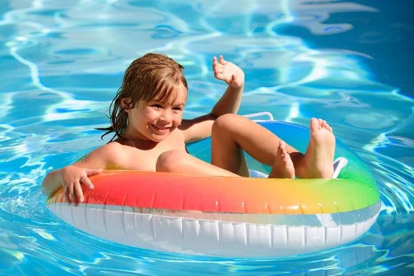 Ragazzo in piscina, rilassarsi nuotare sull'anello gonfiabile e divertirsi in acqua durante le vacanze estive. — Foto Stock