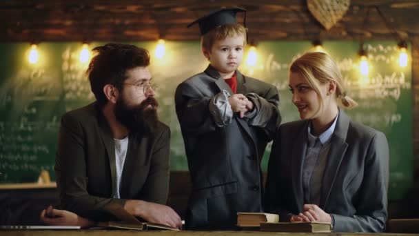 Un écolier et ses parents enseignent à la maison et font leurs devoirs à l'école. Famille étudiant en classe. — Video