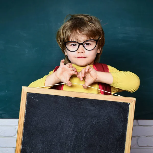 Ritorno a scuola - Concetto educativo. Un simpatico bambino dell'asilo in classe. Bambini della scuola contro lavagna verde. — Foto Stock