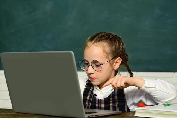 De volta à escola. Aluno trabalhando no computador portátil sobre fundo blackboard. Espaço de cópia de papelão - conceito de escola. — Fotografia de Stock